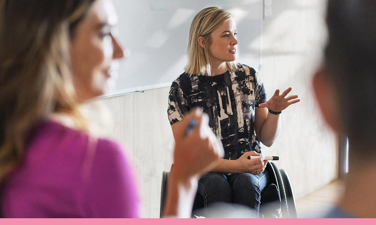 A woman in a wheelchair talks in a meeting.