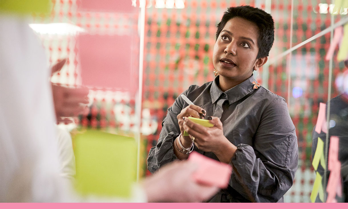 A woman takes notes on a sticky note pad.
