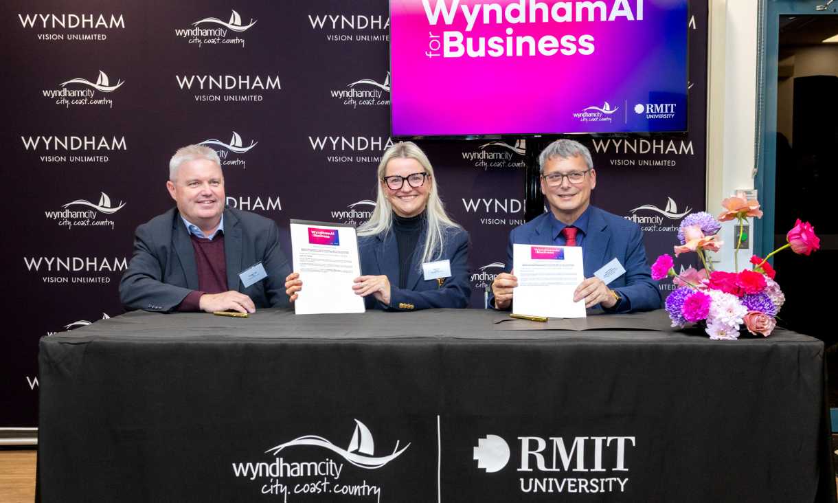 Three people at table holding certificate